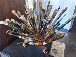 Hedgehog-shaped brush holder filled with paintbrushes