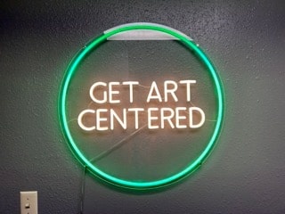 Neon sign reading Get Art Centered