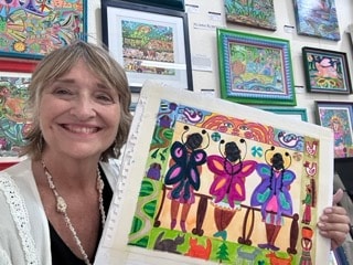 Woman displaying colorful artwork with figures by Robbin Robertson