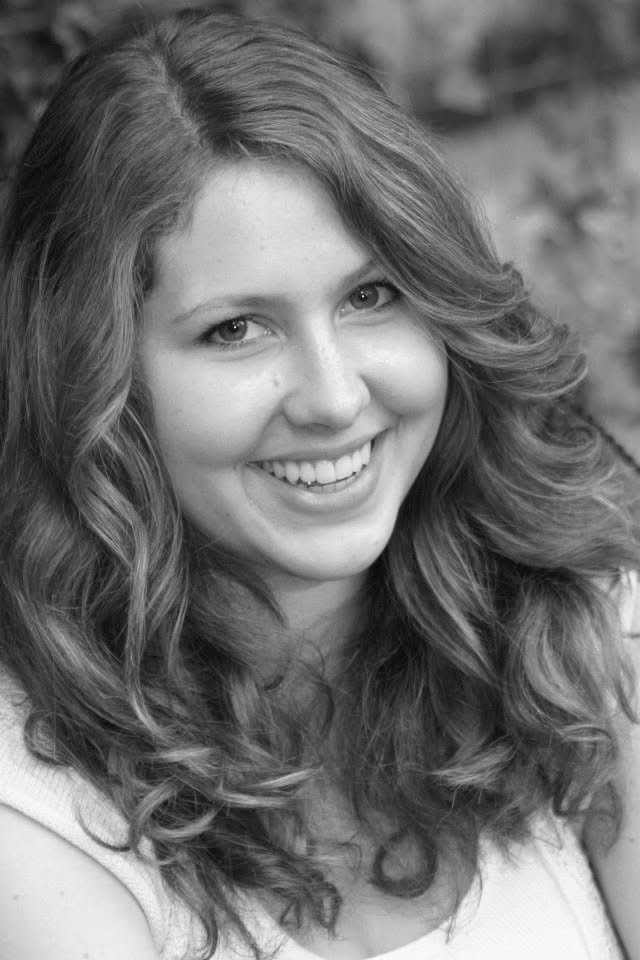 Black and white portrait of a woman with curly hair smiling outdoors