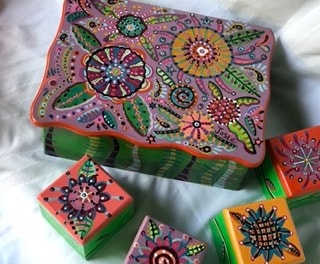 Painted boxes with vibrant mandala and floral patterns in pink, purple and green